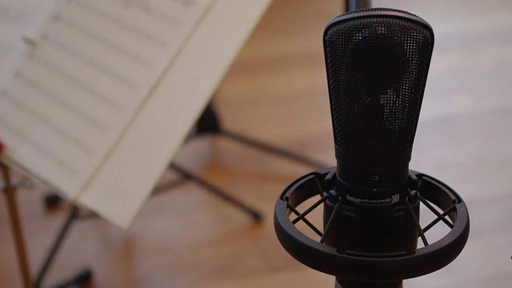 Close-up of a microphone with a blurred music stand in the background.