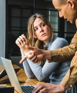 a girl being shown something on a laptop by a guy, signifying a voiceover for explainer videos by Neil Williams, British male voiceover artist with studio